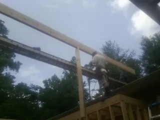 Carpenter setting a ridge beam over a new addition frame — Ice Dam Removal by Roofing Brothers in Titusville
