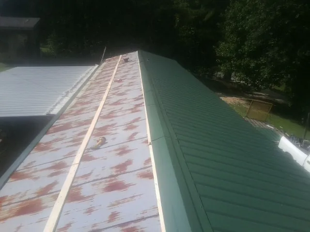 Old rusted panels beside newly installed green metal roofing — Wind Damage Roof Repair by Roofing Brothers in Titusville
