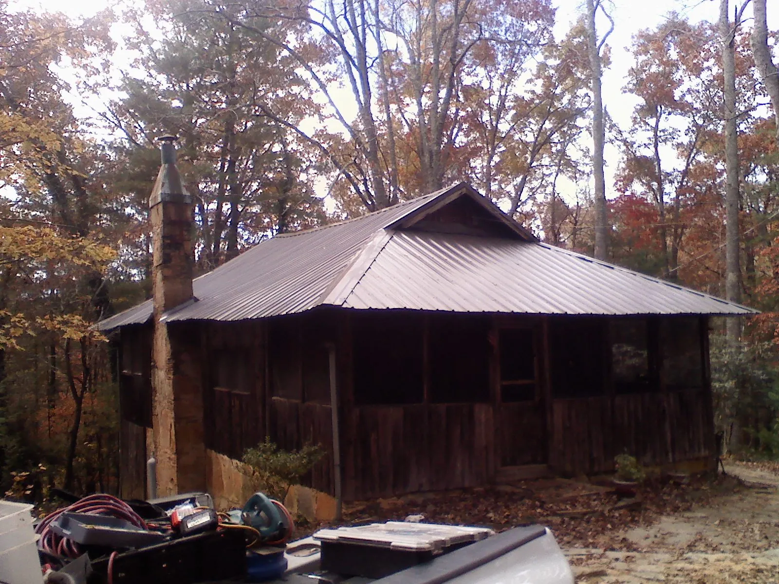 Brown metal hip roof on an old cabin with a stone chimney in Titusville
