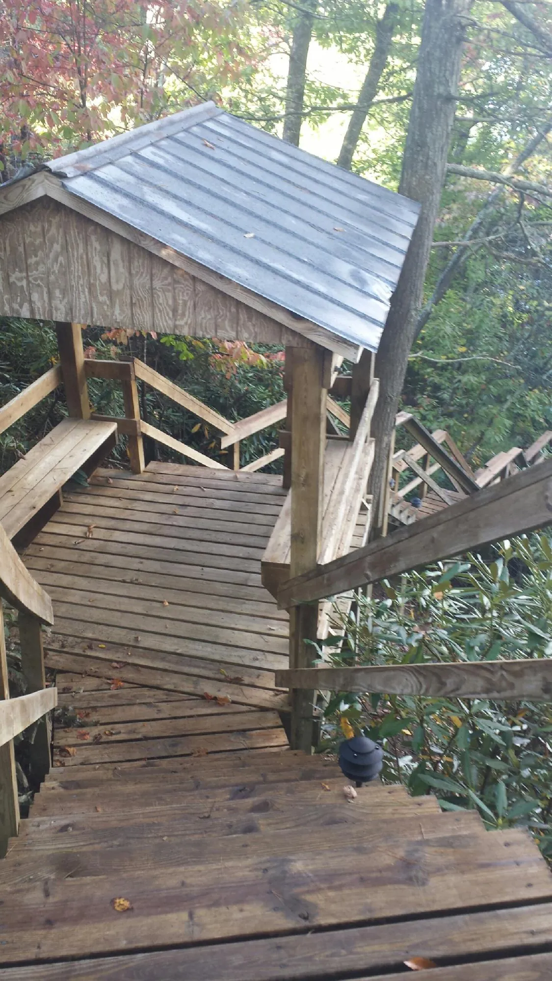 Metal roofed shelter over wooden steps on a wooded walkway — Skylight Repair & Installation work by our crew in Titusville